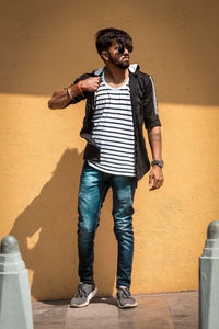 Full length of young man standing against wall