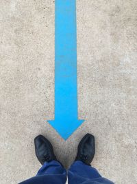 Low section of man standing against blue wall