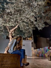 Woman sitting on table by tree