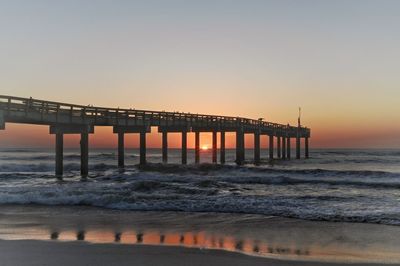 Pier over sea against clear sky during sunset