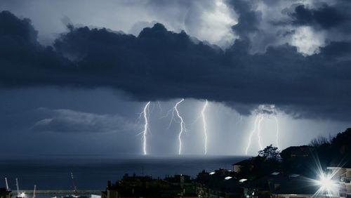 Panoramic view of lightning over illuminated city against sky temporale sul mare in città