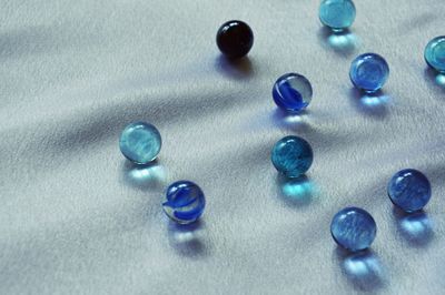 High angle view of blue marbles on white textile