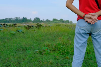 Midsection of woman standing on field against sky