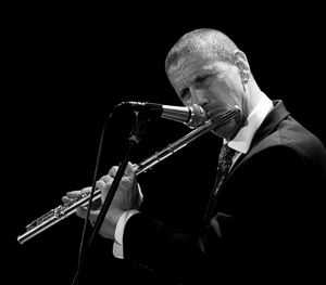 Man playing trumpet against black background