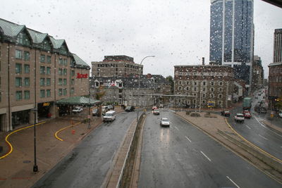 Cars on road by buildings in city during rainy season