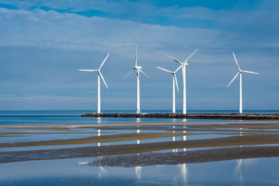 Wind turbines on sea shore against sky