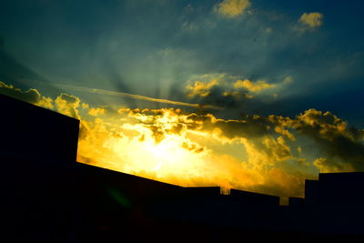 High section of silhouette built structures against cloudy sky