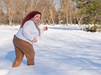 Portrait of young woman standing on snow covered field