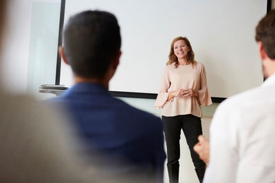 Smiling mature entrepreneur looking away during presentation in office seminar