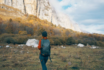 Rear view of man standing on rock against sky