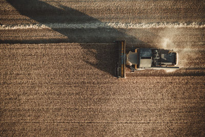 Combine harvester working at sunset from aerial view.