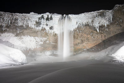 Scenic view of waterfall against mountains during winter