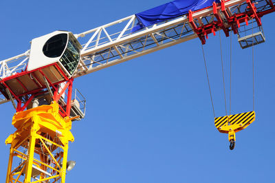 Low angle view of crane against clear blue sky