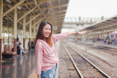 Portrait of smiling young woman standing on railroad platform