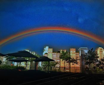 Rainbow over city against blue sky