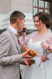 Happy young bride feeding wedding cake to groom outdoors. weeding traditions. lovely couple feed 