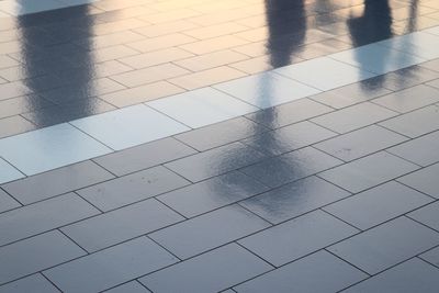 Diffuse reflections of pedestrians walking a marble sidewalk