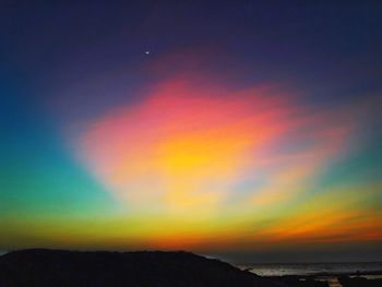 Scenic view of rainbow over sea against sky during sunset