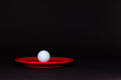 Close-up of golf ball in plate against black background