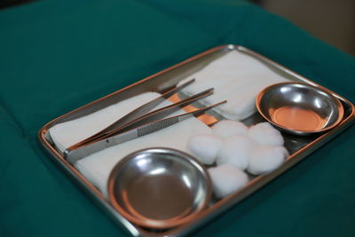 High angle view of cotton balls and equipment with bowls in tray on table in hospital