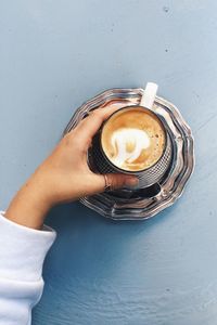 Directly above shot of woman holding coffee cup on table