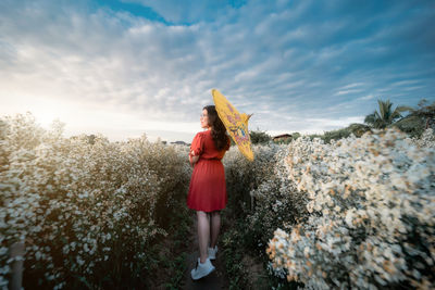 Woman standing by plants against sky