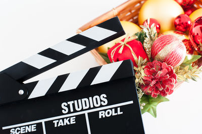 Close-up of film slate with christmas decoration in basket on white background