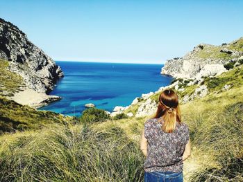 Rear view of woman looking at sea against clear sky