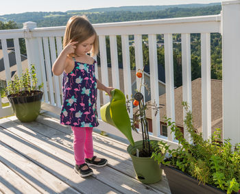 Full length of girl standing by potted plants