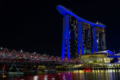 Illuminated bridge over river at night