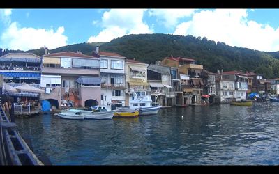 Boats moored in river with buildings in background