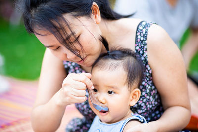 Mother feeding daughter outdoors