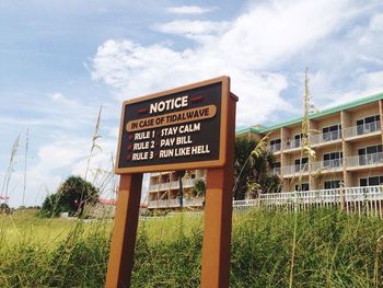 Low angle view of signboard against cloudy sky