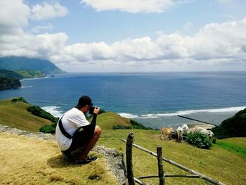 Rear view of man photographing sea against sky