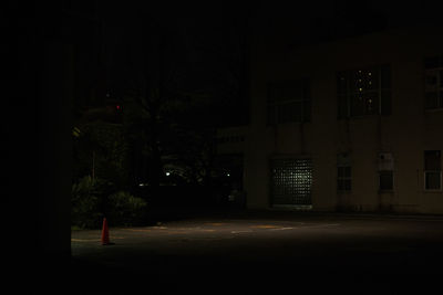 Empty road by illuminated buildings at night