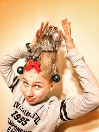 Girl with christmas decorations on hair against wall