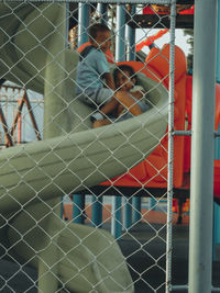 Directly above shot of people sitting on metal fence