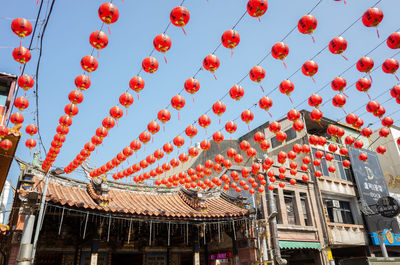 Low angle view of lanterns hanging by building against sky