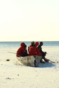 People on beach against clear sky