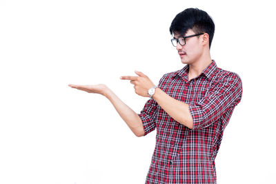 Young woman looking away while standing against white background