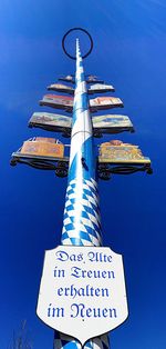 Low angle view of road sign against clear blue sky