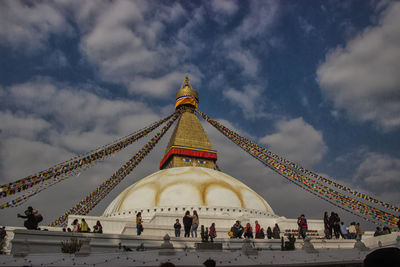 Group of people in temple against cloudy sky
