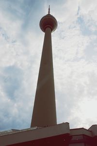 Low angle view of communications tower against cloudy sky