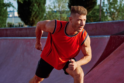 Portrait of young man exercising on field