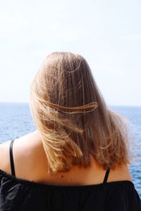 Rear view of woman standing by sea against clear sky