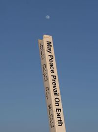 Low angle view of road sign against clear blue sky