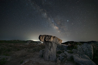 Milky way panorama above a mushroom-shaped rock