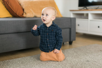 Portrait of cute boy sitting on sofa at home