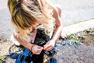 Girl playing outside in a puddle barefoot in sunlight