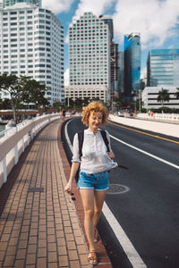 Portrait of young woman walking on street in city